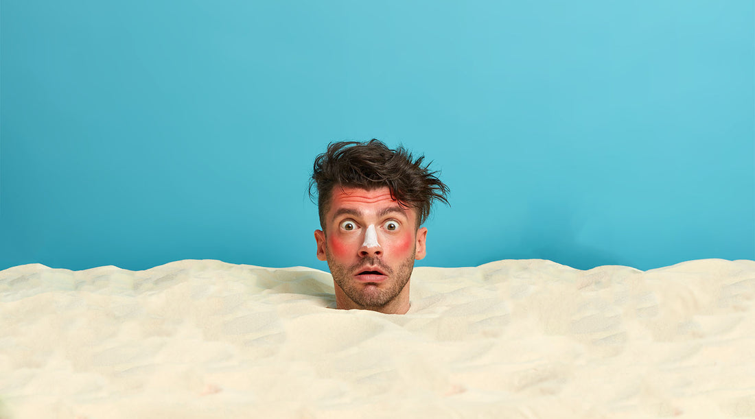 young-man-head-with-sunscreen-cream-face-surrounded-by-beach sand