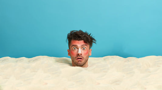 young-man-head-with-sunscreen-cream-face-surrounded-by-beach sand