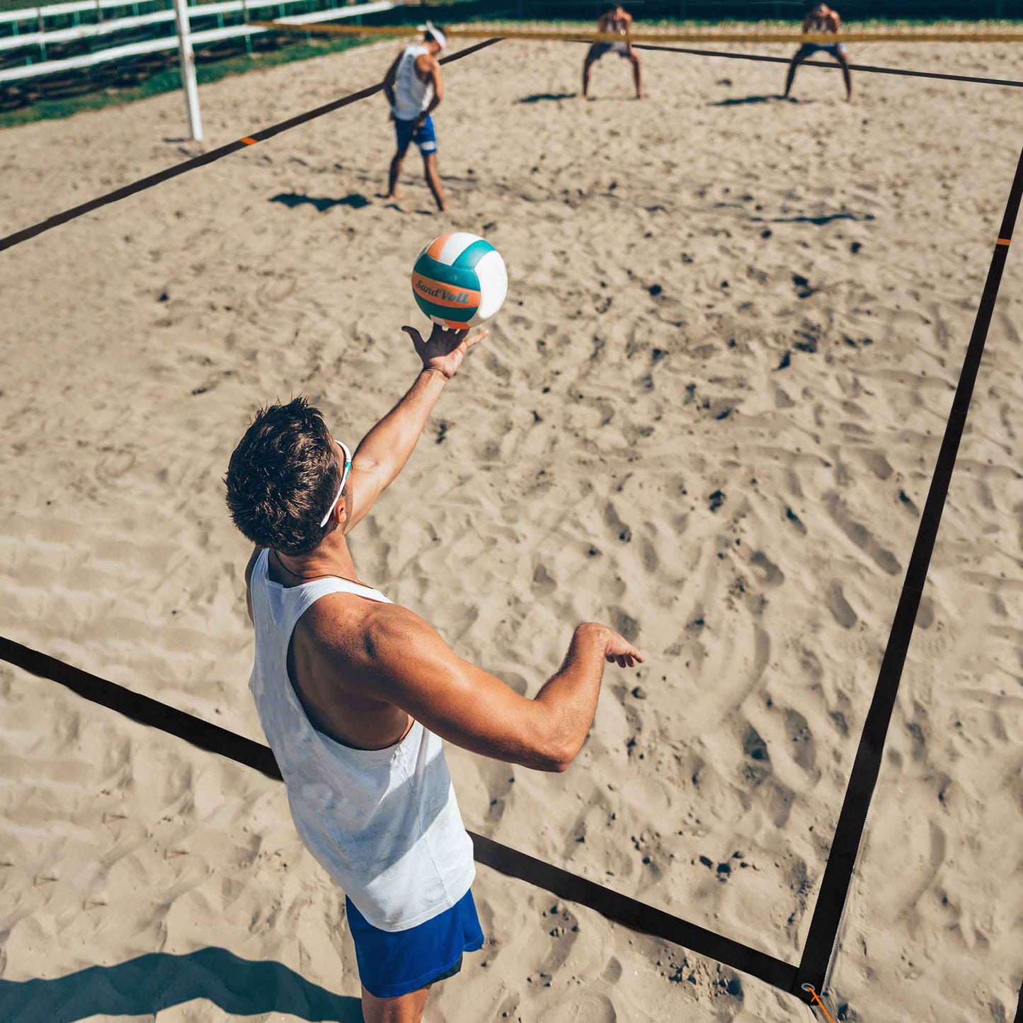 man volleyball player about to serve on sand court
