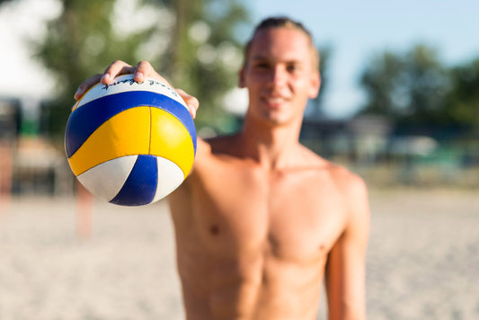 defocused shirtless male volleyball player on the beach holding ball