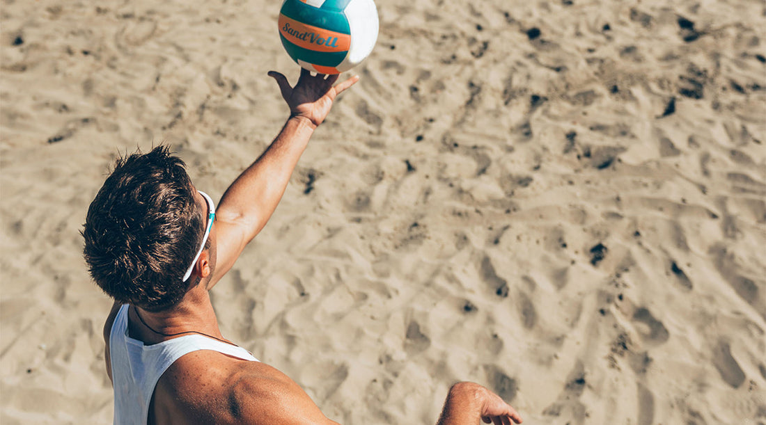 beach volleyball player about to serve a ball